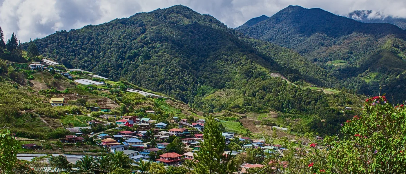 Panoramic view of Kundasang town with highland houses, farms, and mountains in the background.