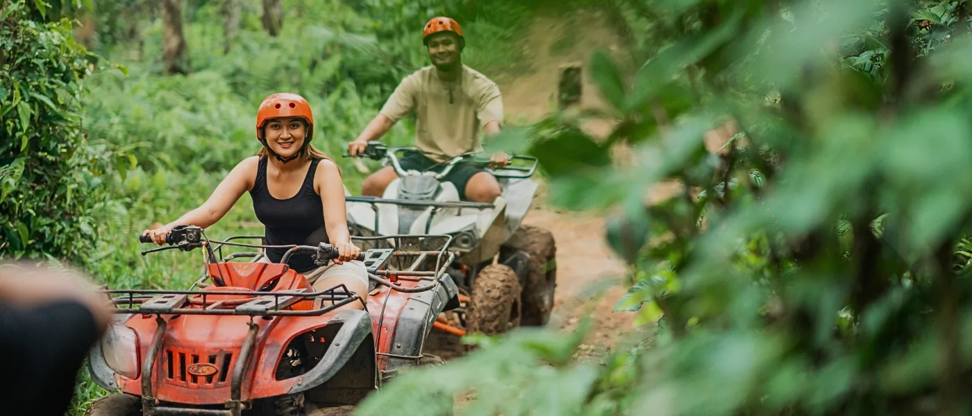 Visitors riding ATVs through a village trail in Kundasang