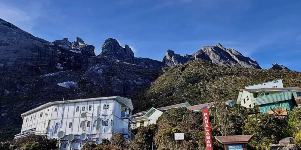 A scenic view of Kinabalu Park with towering mountains rising in the background.