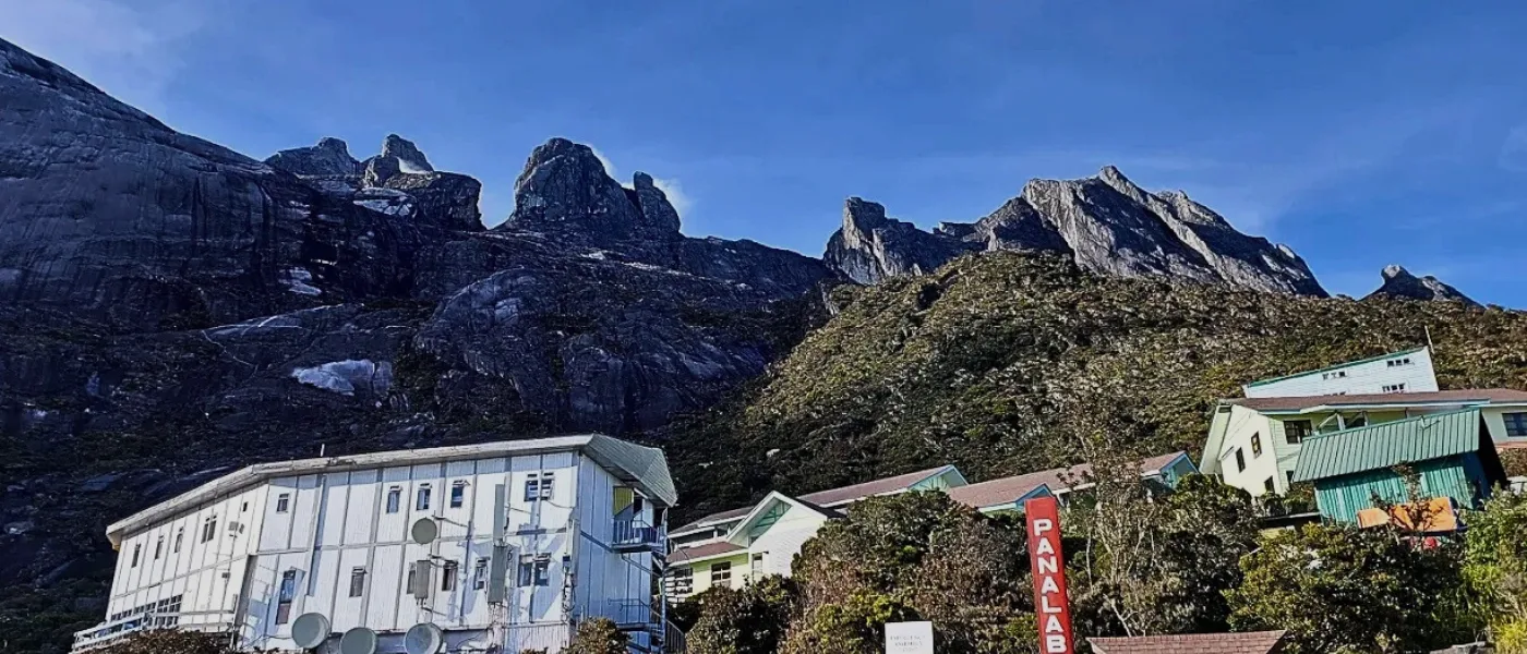 A scenic view of Kinabalu Park with towering mountains rising in the background.