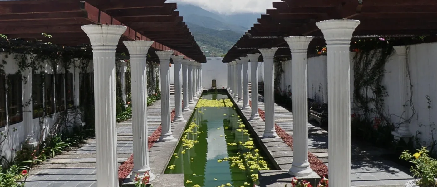 White pillar at Kundasang War Memorial standing tall beside a reflective pond.