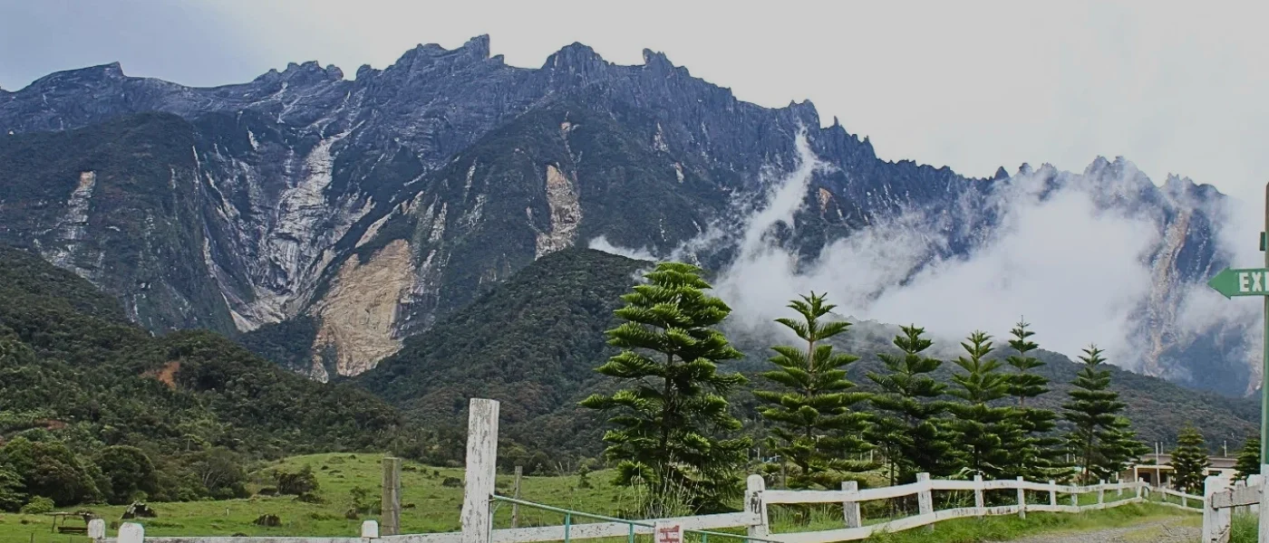 Why Mount Kinabalu’s View Is So Iconic Majestic Mount Kinabalu standing tall against the sky, surrounded by rolling hills and natural beauty