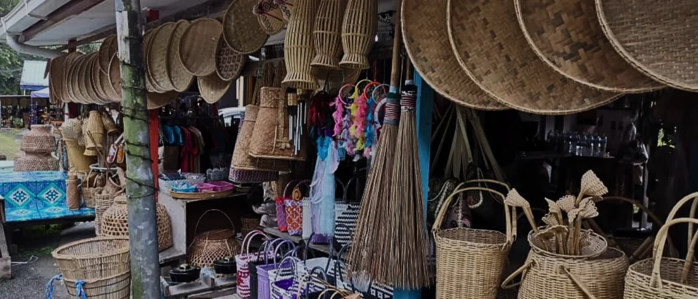 Traditional Woven Crafts at Pekan Nabalu A variety of traditional woven crafts including rattan bags, baskets, winnowing trays, and handmade brooms on display at a stall in Pekan Nabalu