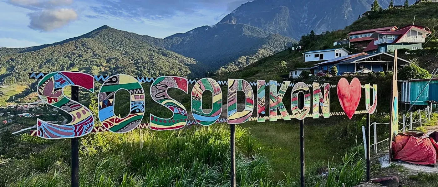 Colorful “Sosodikon Love U” signboard displayed at the top of Sosodikon Hill with mountain scenery in the background